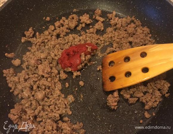 На этой же сковороде обжарить фарш 3-4 минутки. Затем добавить соль, перец, тмин, перец чили, томатну пасту, кипяток, перемешать и тушить 10 минут.