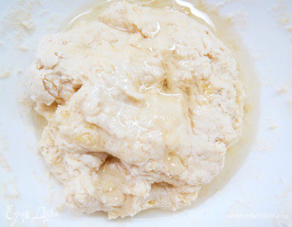 Когда тесто объединится в шар, добавляем растительное масло, снова вымешиваем руками на столе около 6-8 минут.