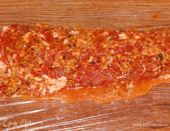 Теперь выстилаем пленкой рабочую поверхность, выкладываем на нее мясо, щедро сдабриваем маринадом с одной стороны, затем с другой. Маринад выкладываем весь.