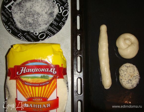 Тесто обмять. Отщипнуть часть теста, скатать колбаску, завязать тесто в узелок и обмакнуть в сахар с маком. Выложить заготовки булочек на смазанный маслом противень.