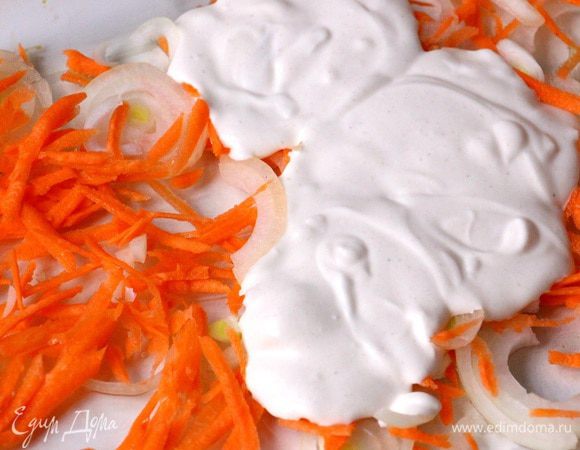 На смазанную оливковым маслом форму равномерно выкладываем лук и морковь, сверху — около трети соуса. 