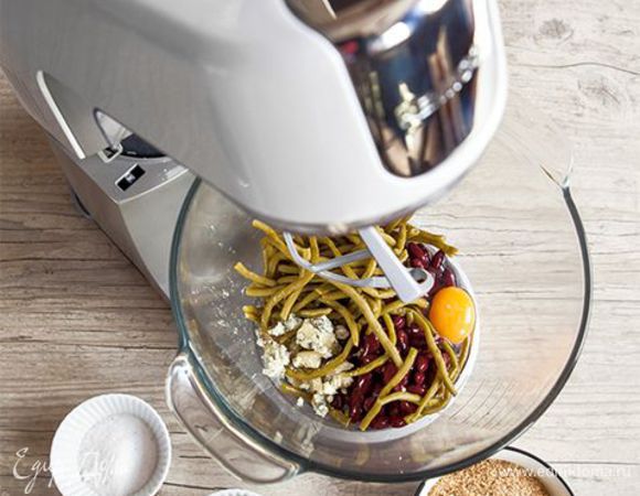 Смешайте размороженную зеленую фасоль и консервированную или отварную. Смесь нужно хорошо вымешать. В этом вам поможет К-образная насадка. Добавьте одно яйцо, половину сухарей и оливкового масла, соль, перец, натертый сыр.
