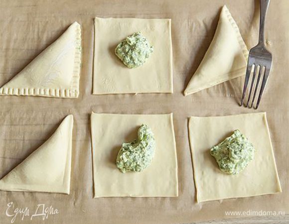 Выложите начинку в центр каждой полоски. Заверните краешек треугольником и защипните края. Так же поступите с остальным тестом и начинкой. Смажьте пирожки сливочным маслом
и выпекайте в разогретой до 190 °С духовке 15 минут. 
