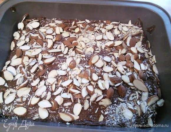 Форму 20×20 см выложить пергаментом, распределить равномерно тесто, посыпать орешками. Пару раз слегка ударить формой об стол, чтобы не было пустот в тесте. 