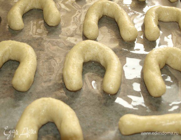 Тесто раскатывать не надо. От теста отделяем кусочек (у меня каждый кусочек 23 г). Скатываем тесто в шарик и ладонями формируем жгут. Складываем жгут, как подкову. Выкладываем на противень, застеленный пекарской бумагой (при желании смазать растительным маслом).