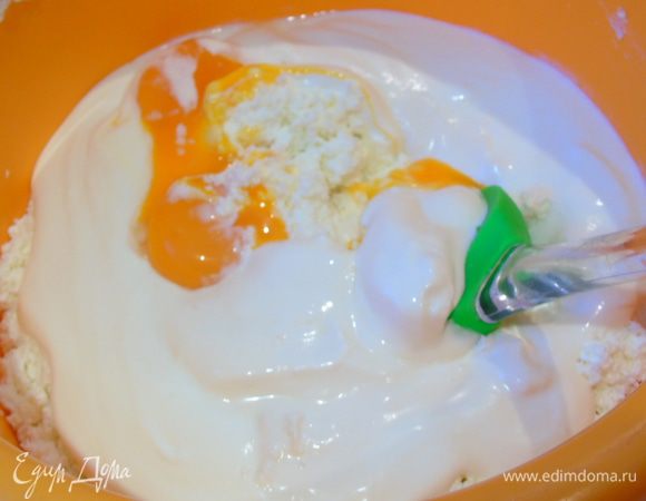 К творогу добавьте сметану и желтки, разотрите ложкой.