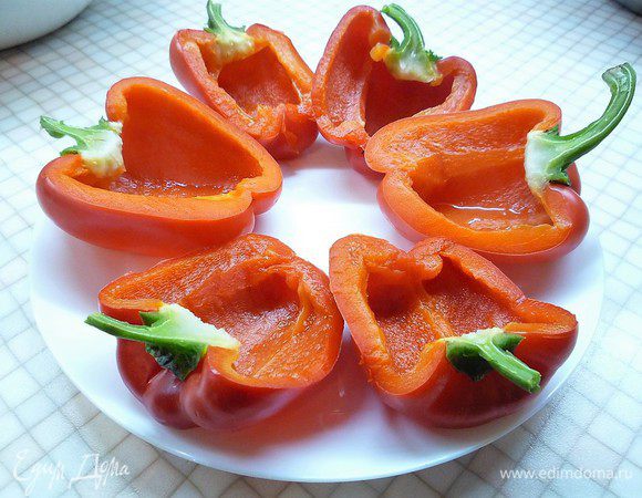 Перец разрезаем вдоль на две части, очищаем от семян (плодоножки оставляем). В кастрюле доводим до кипения воду, опускаем перцы в кипящую воду на 3 минуты, вынимаем и остужаем в холодной воде.