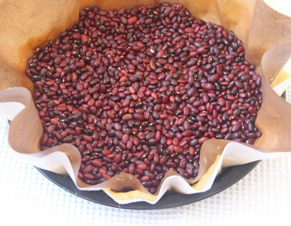 Пласт теста выложить в форму для выпечки (диаметр 26-28 см), сверху положить груз, выпекать при 180°С 15 минут.