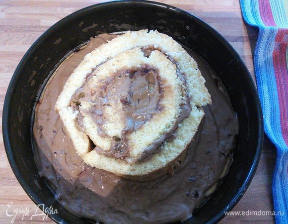 Начинаем сборку торта. Песочный корж служит донышком для конструкции. Скручивая в плотную спираль, выкладываем полосы бисквита, начиная с середины. 