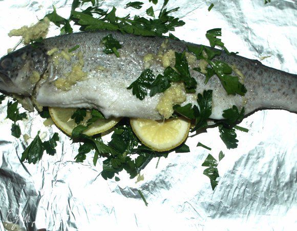 Берем кусок фольги, складываем его вдвое. Фольгу смазать растительным маслом и сверху кладем пару кружочков лимона. Петрушкой фаршируем брюшко рыбы, укладываем туда же несколько долек лимона. Кладем рыбу на подготовленную фольгу с лимоном. Заворачиваем конвертом, так чтоб не было отверстий. Укладываем на противень.