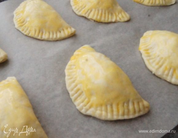 Смазать пирожки эмпанадас желтком, поместить на пергамент. Выпекать в заранее разогретой до 190°С духовке 15 минут.