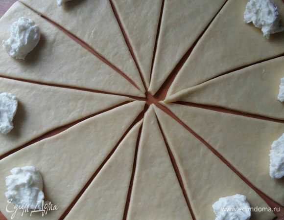 От готового теста отрезаем комочек. Раскатываем на столе. Подсыпать мукой уже не нужно. Режем на 12 частей. Можно на 8 частей. Тогда рогалики будут больше размером. Удобнее всего резать ножом для пиццы. Раскладываем начинку.
Начинка может быть самая разнообразная — творог, варенье, мак, грецкие орехи и т. д.