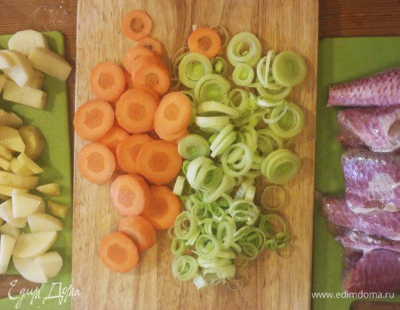 Нарезать овощи тонкими кружками и кубиками. У рыбы отрезать плавники и головы, залить их холодной водой.