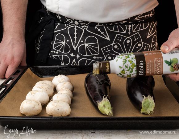 Разогреть духовку до 220°С. Шампиньоны почистить и помыть. На противень выложить баклажаны и грибы. Баклажаны проткнуть в нескольких местах. Все сбрызнуть маслом грецкого ореха Biolio. Запекать грибы в течение 20 минут, а баклажаны — до готовности. Остудить баклажаны и грибы до комнатной температуры.