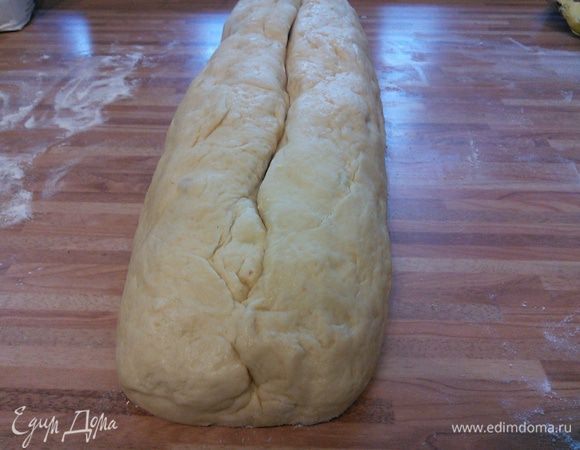 С помощью пергамента скрутить в рулет. Рулет получается очень большой, поэтому его нужно разрезать на 2 части. Переложить вместе с бумагой на противень. Смазать яйцом, взбитым с 1 ст. л. воды, и выпекать в заранее разогретой до 180°С духовке около 45 минут. 
