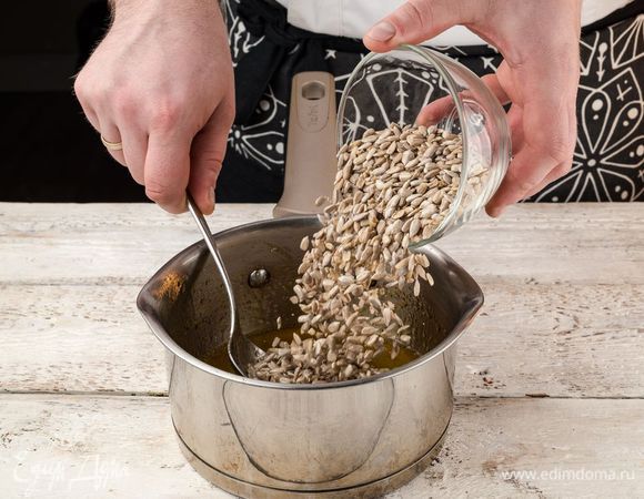 Когда сахар полностью растворится, а масса загустеет и потемнеет, снимите кастрюлю с огня. Добавьте в карамель очищенные семена подсолнечника. Тщательно перемешайте, чтобы карамель равномерно распределилась.
