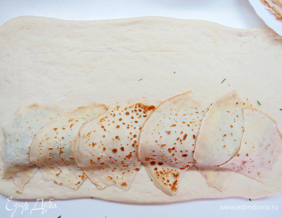 Поверх начинки наискосок выложить слой блинчиков. Для удобства каждый блинчик можно порезать пополам. 