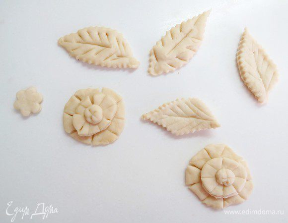 Из оставшегося теста вырезать листочки и цветочки для украшения центральной части пирога.
