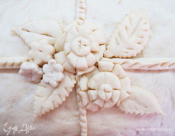 Украсить центр пирога нашими заготовками. Жгут по центру можно немного подрезать по всей длине, чуть прихватывая тесто ножницами.
Оставить пирог на 25 минут для расстойки. Тесто, которое обмялось в процессе формирования пирога, должно снова немного подняться. Включить духовку и нагреть до 220°С.