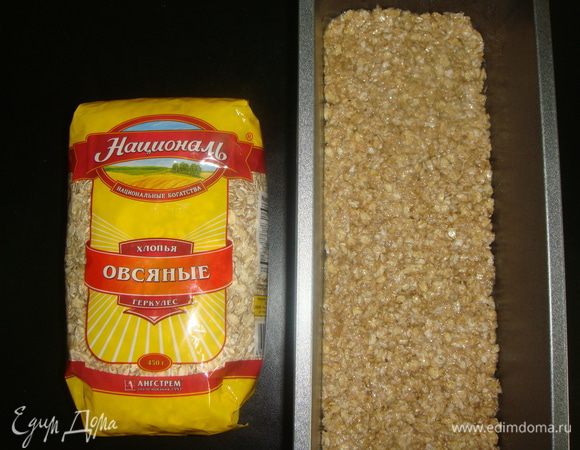 Прямоугольную форму смазать подсолнечным маслом и выложить основу. Разровнять ее ложкой, слегка приминая. Выпекать основу в разогретой до 180°С духовке 15 минут. Выключить духовку и оставить основу еще на 5 минут.