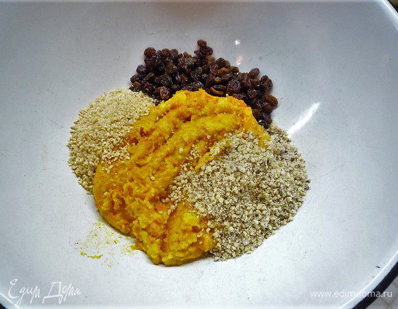 Выкладываем тыквенную массу в чашку, добавляем изюм, измельченные грецкие орехи, миндаль, цедру апельсина. Все хорошо перемешиваем. 