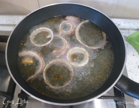 В высокой сковороде разогреть масло для жарки. Опустить в масло кусочек картофеля, чтобы проверить температуру. Когда он подрумянится, можно жарить. Оставшийся лук нарезать колечками, посолить и сбрызнуть уксусом. Смешать фенхель, зиру и муку. Обвалять в этой смеси лук и обжарить до хрустящей корочки. Снимать на бумажное полотенце.