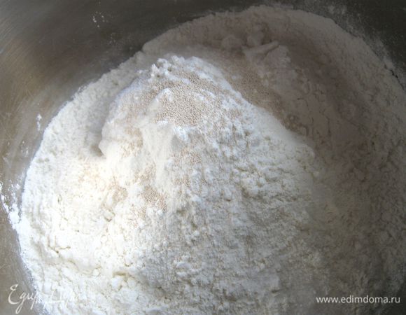 В большой кастрюле смешать пшеничную хлебопекарную муку с дрожжами, солью. 