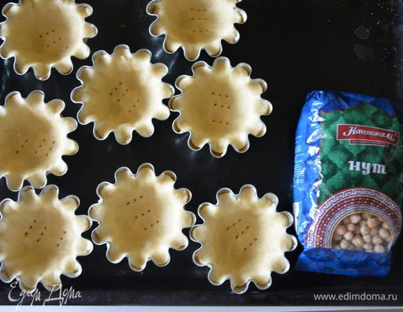 Достать тесто из холодильника, разделить на 8 равных частей. Каждый кусок теста раскатать в круг, выложить в форму, разровнять руками. Формы для корзинок я смазала сливочным маслом, т.к. не знала как себя поведет нутовое песочное тесто. Возможно, смазывать и не нужно. Местами проткнуть тесто вилкой, чтобы не поднялось при выпечке.