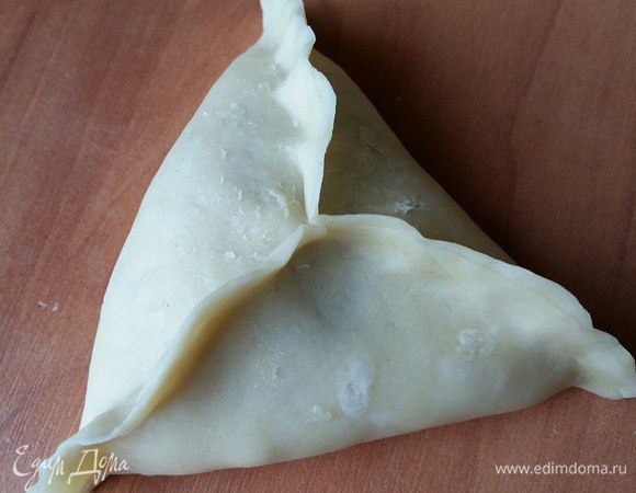 Поднимаем третий край, скрепляем все три края вместе. Придавим уголки. Перевернем швом вниз, получается треугольник. Затем тоже самое повторяем для остального теста. 