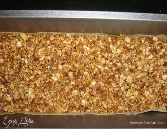 Прямоугольную форму застелить пергаментом и выложить смесь, разровняв ее. Выпекать в разогретой до 150°С духовке 15 минут.
