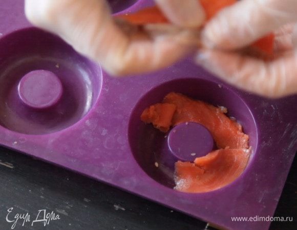 На дно силиконовой формы для пончиков выложить тонкие кусочки филе рыбы.