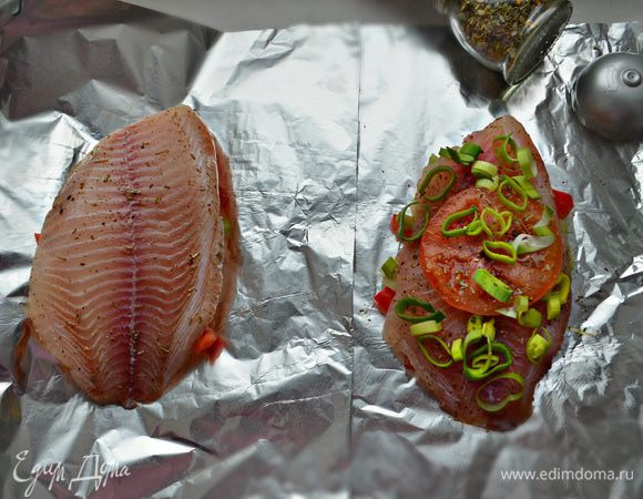 Поверх рыбы уложите кружочек помидора и кольца лука-порея.