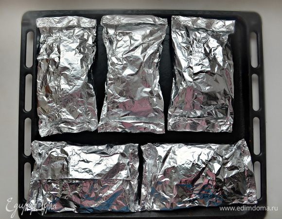 Каждый кусок рыбы заверните в фольгу в виде конверта и уложите на противень. Запекайте рыбу 30 мин. при температуре 180°С.