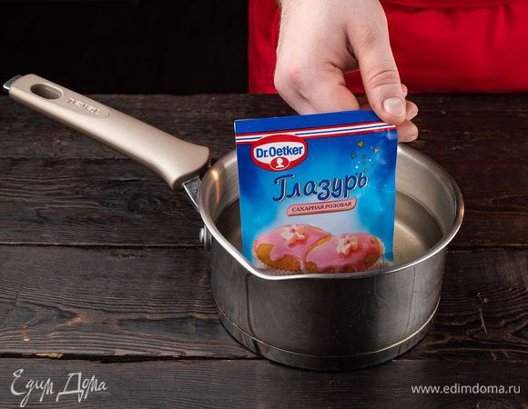 Приготовьте розовую сахарную глазурь Dr. Oetker, опустив упаковку на 5 минут в горячую воду. Выложите упаковку на полотенце и несколько раз надавите на нее, чтобы глазурь стала более мягкой и однородной.