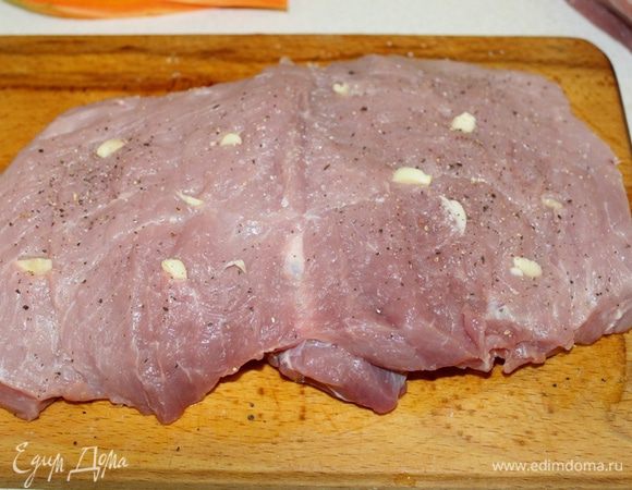 Мясо разрезать как книгу, нашпиговать чесноком. Натереть мясо солью, кориандром и черным перцем.