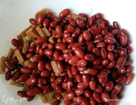 К сухарикам добавляем банку фасоли, обязательно красной консервированной, в собственном соку. Воду из банки с фасолью предварительно слить.