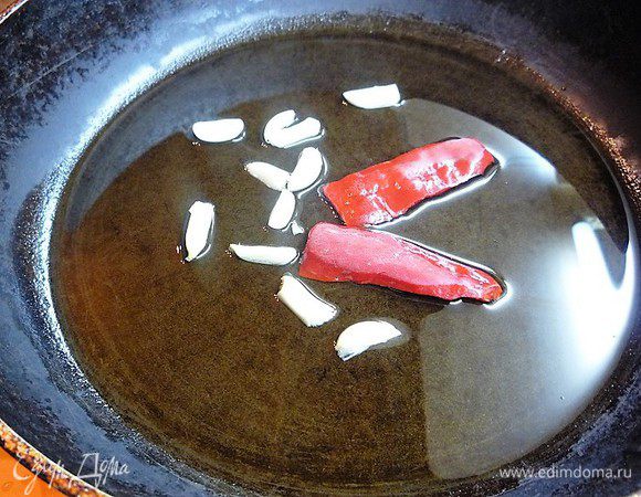 В глубокой сковороде раскаляем оливковое масло и обжариваем чеснок с перцем чили в течение 1 минуты, затем вынимаем и выкидываем.