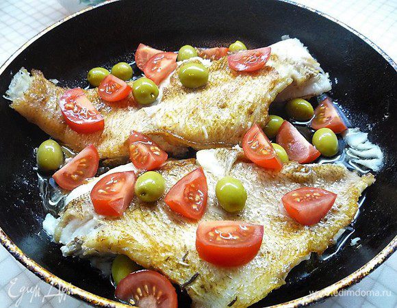 Затем рыбу переворачиваем, добавляем зеленые оливки с косточкой и помидоры черри. 