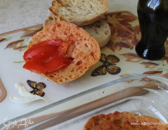 Натрите хлеб чесноком. Разрежьте помидоры пополам, в каждый кусочек хлеба втирайте мякоть помидора, оставляя кусочки мякоти на поверхности. Чем сочнее будут помидоры, тем вкуснее получится пантумака.