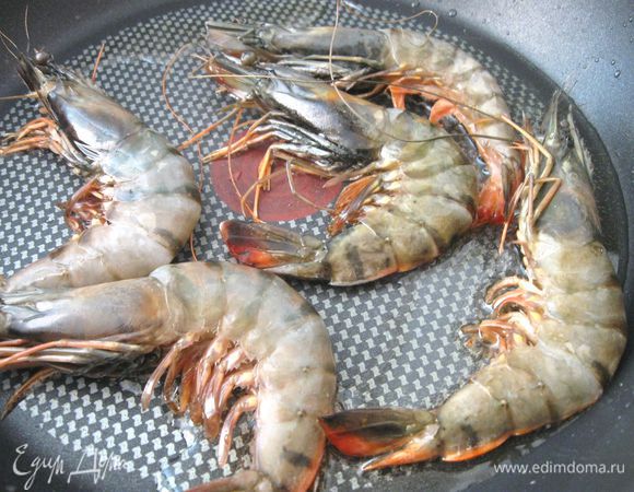 На сковороду поместить креветки на 4-5 минут (обжарить с двух сторон), последние две минуты — под крышкой.