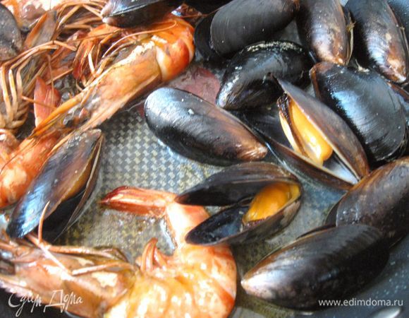Выложить замороженные мидии в сотейник (воду не добавлять), накрыть крышкой и прогреть на сильном огне 3-4 минуты. Затем варить на медленном огне 3-4 минуты, периодически помешивая. Мидии должны раскрыть створки. Мидии со сколами створок не использовать. Сбрызнуть лимонным соком. Выложить на сковородку с креветками. В небольшом количестве кипящей воды сварить щупальца кальмара 1-2 минуты. Вынуть из воды, отложить. Также выложить креветки, мидии со сковороды в теплое место.