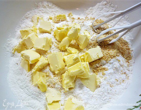 Приготовим тесто сабле. В чашке смешиваем муку, сахарную пудру, молотый миндаль. Добавляем нарезанное кусочками сливочное масло и все перетираем в крошку.