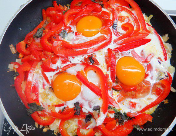 Распределить овощную смесь по жаропрочным формам. Если сковорода пригодна для приготовления пищи в духовке, то оставить овощи в этой же сковороде. В овощах сделать углубления и разбить туда яйца. Сверху полить яйца сливками, примерно по 1 ст. л. на яйцо.