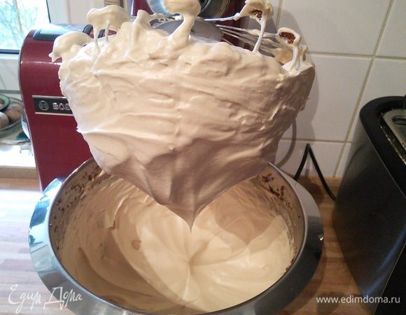 Когда белки вбиты до плотных пиков (но не перевзбиты!) начинаем тонкой струйкой вливать карамель. Нужно стараться лить карамель на стенку чаши комбайна, иначе она может разбрызгаться и приклеиться к венчику. Не переставая взбивать доводим белки до образования очень плотной блестящей меренги и ее охлаждения до комнатной температуры.