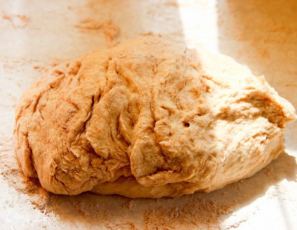 В поднявшееся тесто добавляем столько муки, сколько «возьмет». Тесто должно быть не липким. Хорошо вымешиваем. Раскатываем половину теста в тонкий пласт.