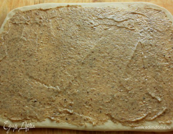 Подошедшее тесто  выложить на присыпанную мукой поверхность и раскатать в прямоугольник 40 х 30 см. С помощью шпателя равномерно нанести на тесто ореховую смесь. 