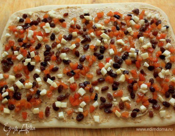 Сверху распределить пропитанные сухофрукты и яблоко. Скатать тесто в рулет по длинной стороне.