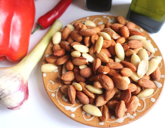 Миндаль бланшировать. Для этого опустить миндаль в слегка кипящую воду на 3-4 минуты. Откинуть на дуршлаг, дать немного остыть, снять шелуху, дать миндалю полностью обсохнуть на бумажной салфетке. Часть миндаля оставить сырым, часть — обжарить на сковороде, смазанной оливковым маслом, до светло-золотистого цвета. Во время обжаривания миндаля (через 1-2 минуты) положить на сковородку кедровые орешки, обжарить. Можно взять вместо кедровых орехов фундук, у которого тоже, как у миндаля, надо предварительно снять шелуху.