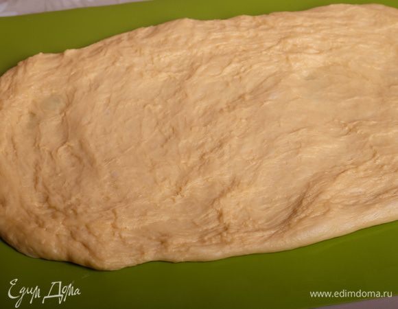 Выложить тесто на рабочую поверхность (не присыпая мукой), растянуть его, формируя подобие прямоугольника. Удобнее всего работать с тестом на силиконовом коврике.