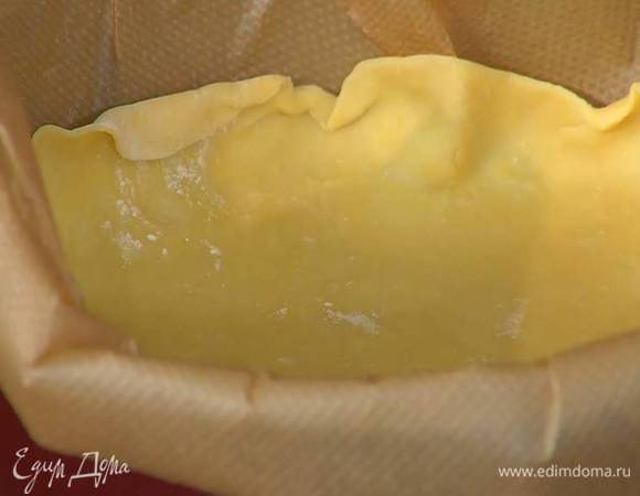 Рабочую поверхность присыпать мукой, раскатать тесто в тонкий пласт и выложить в форму, выстеленную бумагой для выпечки, так чтобы получились бортики.